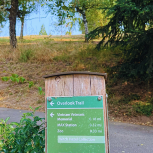 A trail marker post with Overlook Trail highlighted in green at the top