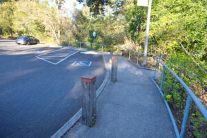 A picture of the 2 accessible parking spaces in the main lot adjacent to the visitor center from the ramp that leads to the courtyard.