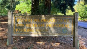 a wooden sign marking the start of wildwood trail, the vietnam veterans memorial, and parking lot.